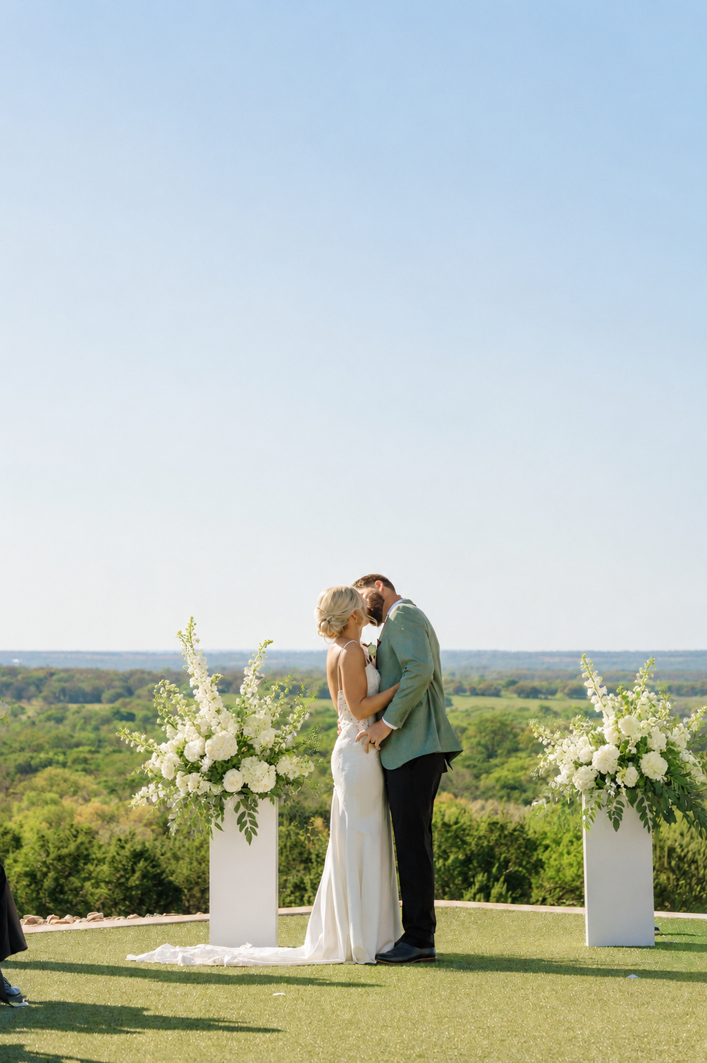 Bride and groom sharing a kiss at Diamond A Ranch with rolling Texas countryside stretching behind them during golden hour.